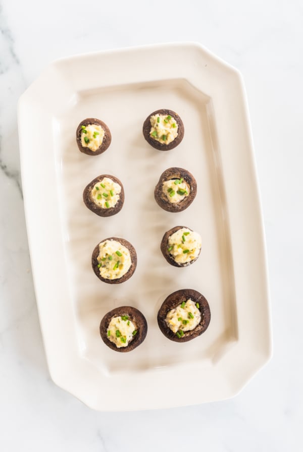 A white platter full of Boursin stuffed mushrooms.