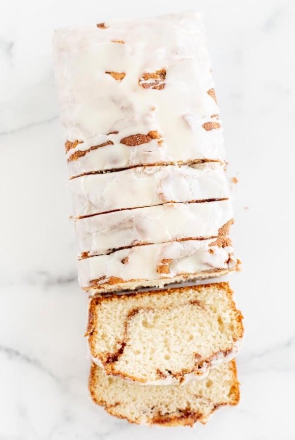 A loaf of [content00inject]168[content00inject]，Cinnamon Roll Bread, covered in icing and sliced on a marble surface