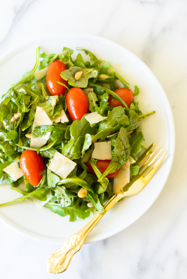 A white plate with insalata mista and a gold fork.