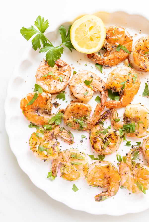 Lemon pepper shrimp on a round white serving platter.